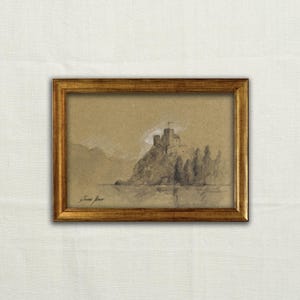 Puede incluir: Un dibujo al carboncillo y tiza blanca sobre papel beige enmarcado que representa un castillo sobre un acantilado rocoso frente al agua. La obra está dentro de un marco rectangular dorado con una firma visible en la esquina inferior izquierda.