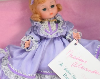 May include: A Madame Alexander doll from The Southern Children Series named Rachel, featuring auburn hair and a lavender dress with white lace trim. The doll is presented in a white box with pink tissue paper and includes a white product tag.