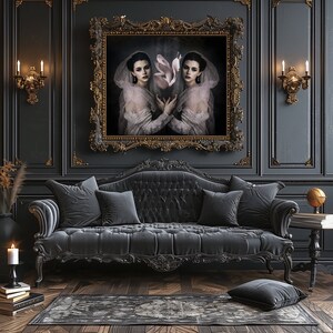May include: A luxurious living room with a dark gray tufted sofa, matching pillows, and a patterned rug. A large framed portrait hangs above the sofa. The walls are dark gray with gold accents, and sconces flank the artwork. A candle and books sit on the floor.