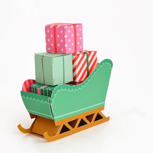 May include: A green paper sleigh with a gold base, carrying four wrapped gifts. The gifts are decorated with red and white stripes, pink polka dots, and green stripes.