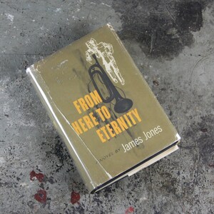 Op de afbeelding: Een vintage paperback met een groene kaft met een zwart-witte illustratie van een soldaat en een trompet. De titel van het boek is "From Here to Eternity" van James Jones.