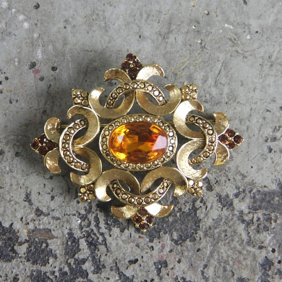 Signed Oscar de la Renta Gold Brooch with a fleur de lis design, a large center lemon quartz stone, and 16 garnet stones, vintage