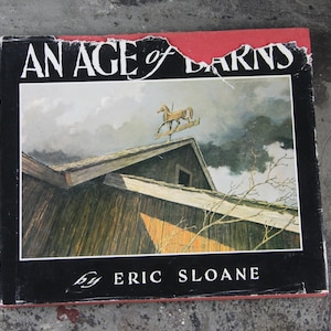 Könnte beinhalten: Ein Vintage-Buch mit dem Titel "An Age of Barns" von Eric Sloane. Der Umschlag zeigt ein Aquarellbild einer verwitterten Scheune mit einem Wetterhahn aus Holz in Form eines Pferdes auf dem Dach.