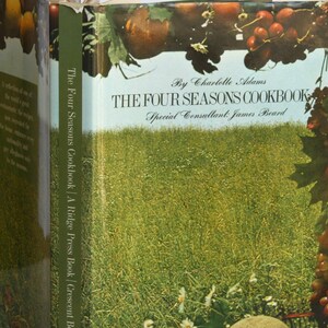 May include: The Four Seasons Cookbook by Charlotte Adams with a special consultant James Beard. The cover features a green field with white flowers, a blue sky, and a vine with red and green grapes.