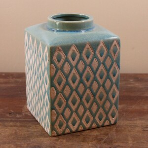 Pode incluir: Um vaso quadrado de cerâmica com um esmalte azul claro e um padrão de diamantes brancos. O vaso tem um acabamento de esmalte craquelado.