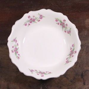 Puede incluir: Tazón de cerámica blanco con borde festoneado y diseño floral con flores rosas y hojas verdes.