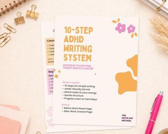 May include: A cream-colored booklet titled "10-Step ADHD Writing System" with pink and orange accents. The booklet is accompanied by a pink pen, gold paper clips, and a spiral notebook. The text includes "Inspired by Occupational Therapy Principles and DBT."