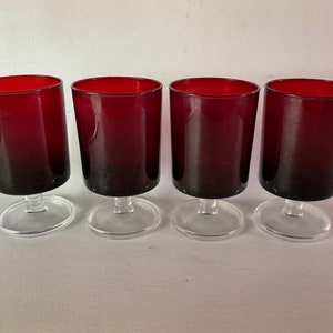May include: Set of four clear glass stemmed drinking glasses with a dark red ombre effect.