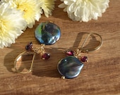 Freshwater pearl coin with garnet dangle earrings on gold leverback ear wires.