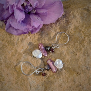 May include: A pair of silver earrings with a cluster of white and purple freshwater pearls and garnet beads.