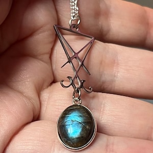 Puede incluir: Un collar de plata con un colgante que presenta un sello de plata y una piedra de labradorita azul.