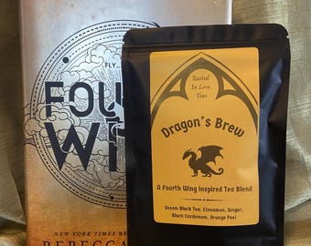 May include: A black pouch of Dragon's Brew tea with a yellow label featuring a dragon graphic and the text Rooted In Love Teas, A Fourth Wing Inspired Tea Blend, Assam Black Tea, Cinnamon, Ginger, Black Cardamom, Orange Peel next to a book.
