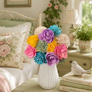 May include: A bouquet of colorful wooden flowers in a white ribbed ceramic vase. The arrangement features blooms in shades of bright yellow, hot pink, purple, teal, light green, and cream, all with visible wood grain textures and layered petals.