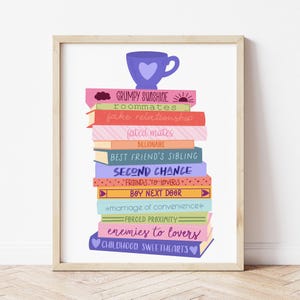May include: A stack of colourful books with different relationship titles, including "Grumpy Sunshine", "Roommates", "Fake Relationship", "Fated Mates", "Billionaire", "Best Friend's Sibling", "Second Chance", "Friends to Lovers", "Boy Next Door", "Marriage of Convenience", "Forced Proximity", "Enemies to Lovers", and "Childhood Sweethearts". A purple teacup with a heart sits on top of the stack.