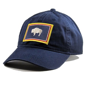 May include: A navy blue baseball cap with a yellow and red embroidered patch featuring the state flag of Wyoming. The patch shows a white silhouette of a buffalo on a blue background.