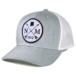 Peut inclure: Un chapeau de camionneur gris et blanc avec un patch noir et blanc représentant les lettres "NM" avec des flèches croisées et l'année "1912" en dessous.