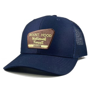 May include: A navy blue trucker hat with a brown patch that reads "Mount Hood National Forest Oregon".