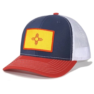 Peut inclure: Un chapeau de camionneur bleu marine et rouge avec un filet blanc à l'arrière. Le chapeau présente un patch jaune avec le drapeau de l'État du Nouveau-Mexique.