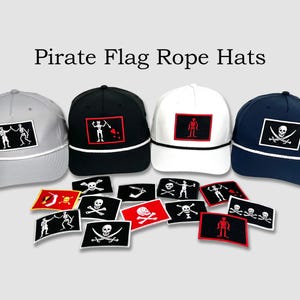 Peut inclure: Quatre chapeaux en corde à drapeau de pirate en gris, noir, blanc et bleu marine. Chaque chapeau présente un design de drapeau de pirate brodé différent. Une variété de patchs de drapeau de pirate brodés sont dispersés devant les chapeaux.