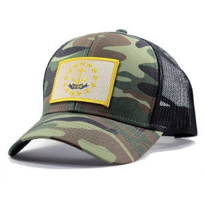 May include: A camouflage trucker hat with a black mesh back. The hat features a patch of the Rhode Island state flag with the words "HOPE" on a yellow ribbon.