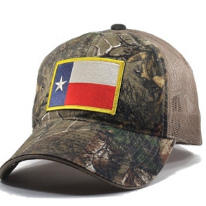 May include: A camouflage trucker hat with a brown mesh back and a yellow embroidered patch of the Texas state flag.