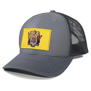 May include: A gray and black trucker hat with a yellow patch featuring the state seal of New Jersey.