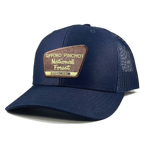 May include: A navy blue trucker hat with a brown patch that reads "Gifford Pinchot National Forest Washington".