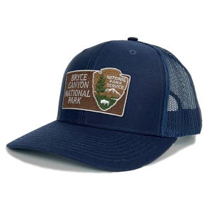 May include: A navy blue trucker hat with a brown patch featuring the Bryce Canyon National Park logo. The logo includes the text "Bryce Canyon National Park" and "National Park Service".