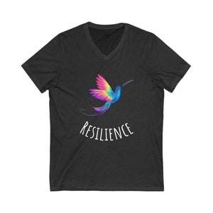 Puede incluir: Una camiseta de cuello en V gris oscuro con un gráfico de colibrí colorido y la palabra "RESILIENCE" impresa en blanco debajo del colibrí.