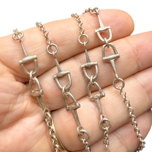 Puede incluir: Una taza de cerámica blanca con un asa negra y el texto "But First, Coffee" en negro y negrita. La taza está sobre una superficie de madera. La taza mide aproximadamente 10 cm de alto.