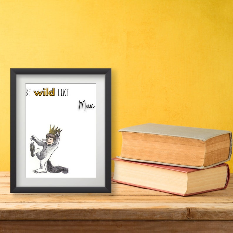 Op de afbeelding: Een zwart ingelijst afdruk met een witte achtergrond. De afdruk toont een zwart-witte illustratie van een personage met een kroon en de tekst "Be wild like Max".