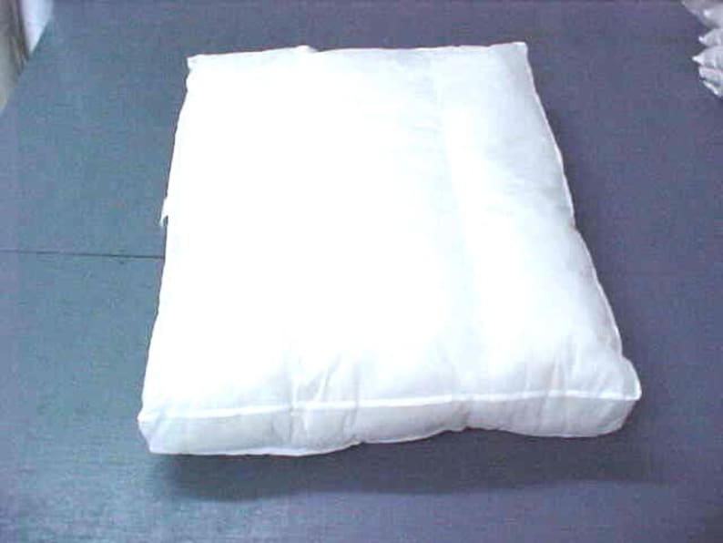 A white rectangle dog bed insert laying on a blue background.