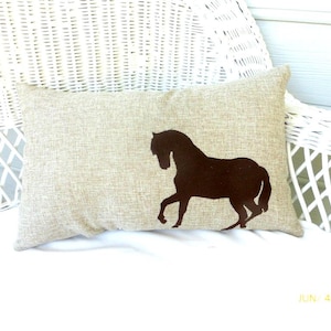 Lite brown poly burlap lumbar pillow with a horse embroidered in dark brown off to one side at the bottom.