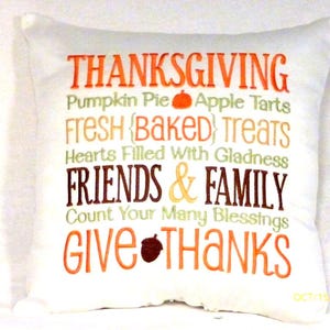 Fall pillow has a white background and subway tile style embroidered words.   The 1st line is, THANKSGIVING, in orange, 2nd line in small green embroidery is, Pumpkin Pie a orange pumpkin and apple tarts, 3rd line Fresh Baked Treats in gold, 4th line Hearts filled with gladness in green, 5th in a large font and brown thread is Friends &  Family, 6 in small green letter is Count your many blessings, 7 in large orange is Give Thanks with a  brown acorn between the words.