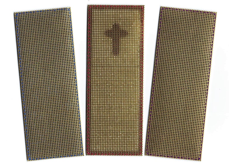 May include: Three rectangular pieces of beige canvas with different colored borders. The canvas has a grid pattern and the borders are blue, red, and purple.