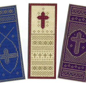 May include: Three embroidered bookmarks with gold trim. The bookmark on the left is blue with a gold cross. The middle bookmark is cream with a red cross and gold trim. The bookmark on the right is purple with a gold cross in a circle.