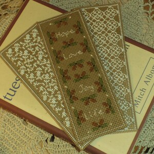 Può includere: Tre segnalibri fatti a mano con diversi disegni ricamati. I segnalibri sono realizzati in tessuto beige con ricami bianchi e marroni. I segnalibri sono sopra un libro con il titolo "Tuesdays with Morrie" di Mitch Albom.