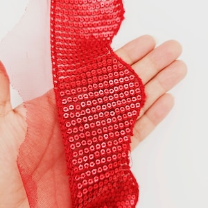 May include: Red sequined trim with a scalloped edge and a sheer mesh backing.