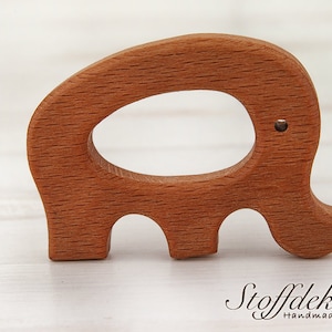 May include: A wooden elephant teether with a smooth, natural finish. The teether is made of beech wood and is certified safe for babies. The teether is shaped like an elephant with a large oval opening in the middle. The teether is a great way for babies to soothe their gums and explore different textures.