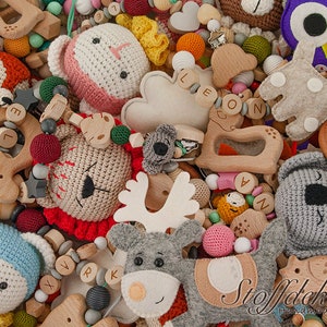 Pu&ograve; includere: Primo piano di una variet&agrave; di giocattoli per bambini fatti a mano, tra cui animali all'uncinetto, morsi di legno e una renna di feltro. I giocattoli sono disposti in modo colorato e giocoso, con una variet&agrave; di trame e colori. L'immagine include anche diverse etichette con testo in tedesco, tra cui "Oeko-Tex 100", "Schadstoff Frei" e "Merino Wollfilz".