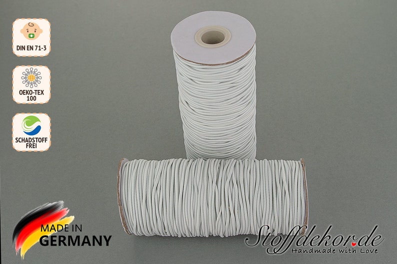 Pu&ograve; includere: Due bobine di cordoncino elastico bianco, ciascuna avvolta attorno a un tubo di cartone. Le bobine sono etichettate con "DIN EN 71-3", "OEKO-TEX 100", "SCHADSTOFF FREI" e "MADE IN GERMANY".