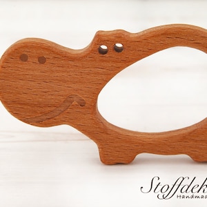 May include: A wooden hippopotamus teether for babies. The teether is made of beech wood and is finished with bio linseed oil. It is certified safe for babies and meets the DIN EN 71-3 safety standard. The teether is also certified by the FSC, which means that the wood comes from sustainably managed forests.