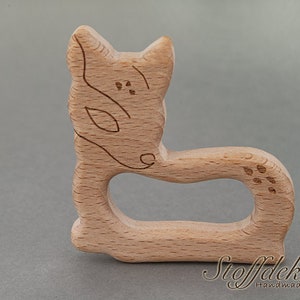 May include: A wooden fox-shaped teether for babies. The teether is made of natural beech wood and is safe for babies to chew on. It is also certified by FSC and Schadstoff Frei.