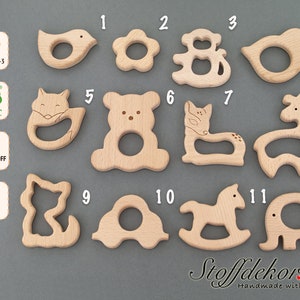 May include: Twelve wooden teethers in various animal shapes, including a bird, flower, monkey, deer, fox, bear, cat, giraffe, and elephant. The teethers are made of natural wood and are designed for babies to chew on.