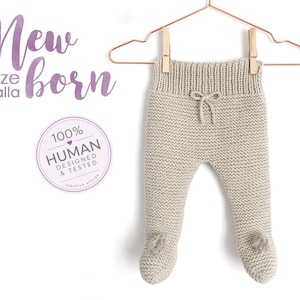 May include: Beige knit newborn trousers with a ribbed waistband, a small decorative drawstring bow at the centre, and integrated footies. The text New size talla born and a circular 100% HUMAN DESIGNED & TESTED badge are visible.