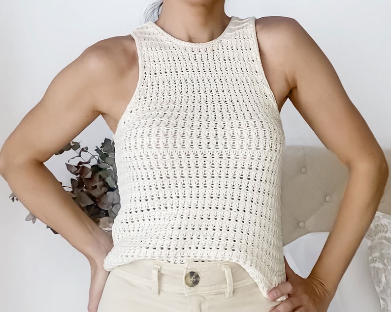 May include: A white crochet tank top with a high neckline and a loose fit.