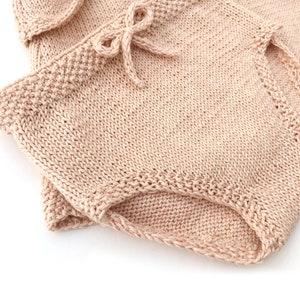 May include: A pair of knitted shorts in a light pink color. The shorts have a tie at the waist and are made of a soft, comfortable fabric.