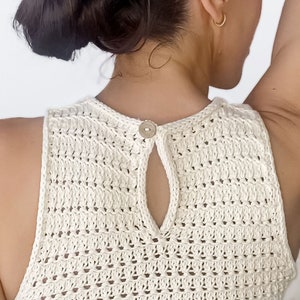 May include: White crochet tank top with a button closure at the back.