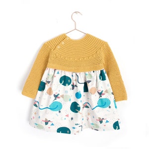 May include: A yellow crocheted sweater dress with long sleeves and a white skirt with a colorful geometric pattern.