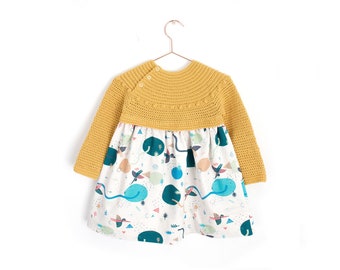 May include: A yellow crocheted sweater dress with long sleeves and a white skirt with a colorful geometric pattern.